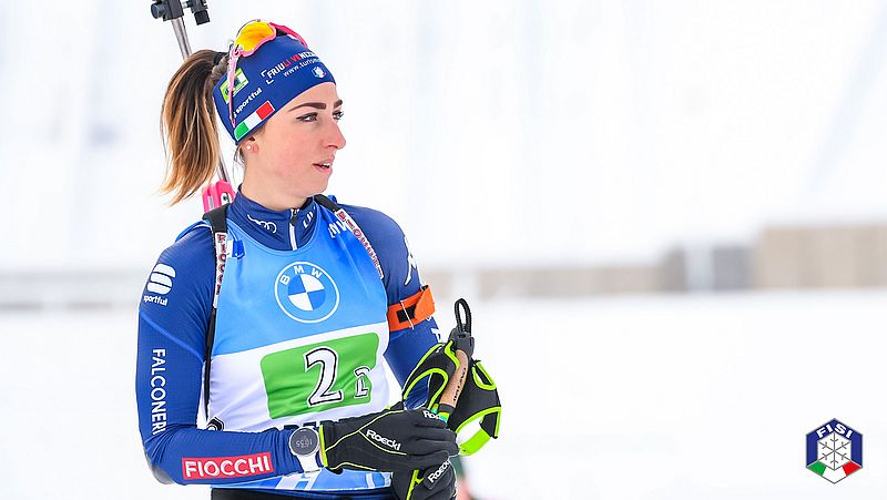 Лиза Виттоцци стоит на снегу со своим лыжным снаряжением.