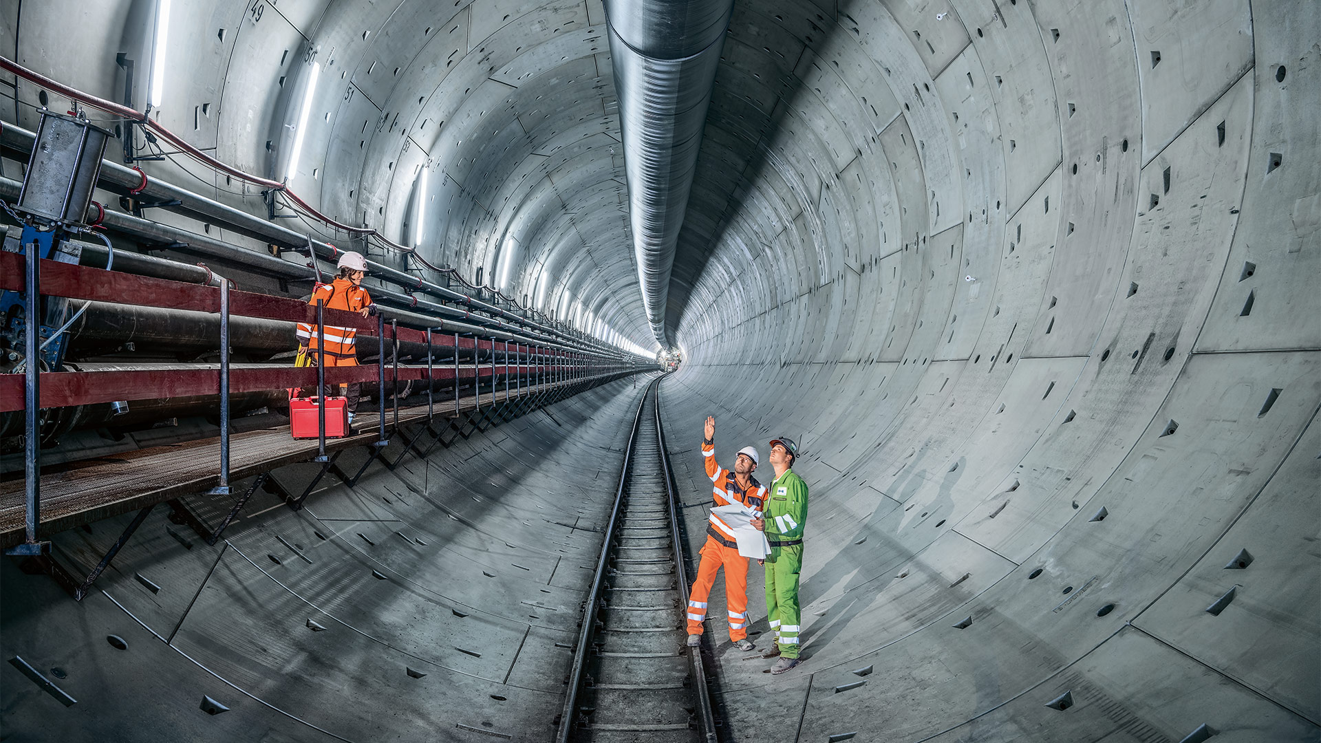 Drei Baustellenmitarbeiter stehen in einer Tunnelröhre